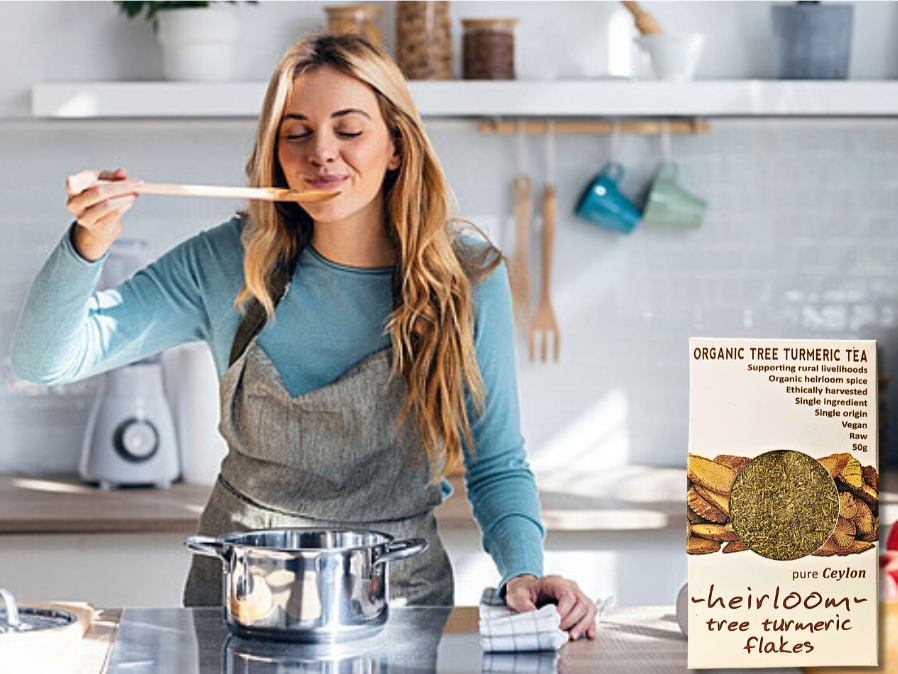 Woman tasting soup in a modern kitchen; next to her is a pack of Organic Tree Turmeric Tea (heirloom tree turmeric flakes).